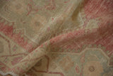 The soft, distressed texture of a vintage Oushak rug showing low pile and visible knot heads.