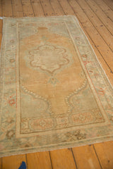 Angled view of a distressed Oushak runner showing its scalloped medallion and pale silver-green border.