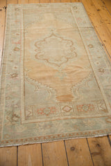 Angled view down the length of a distressed Oushak runner, showcasing its soft gold and sand abrashed field.