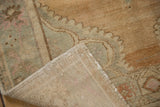 Folded corner of a distressed Oushak rug showing the hand-knotted foundation and low pile.