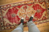 Personal view of a distressed Oushak runner's worn texture and red geometric medallion.
