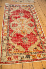Angled view of a distressed Oushak runner, highlighting the worn texture of its red and beige geometric pattern.