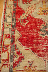 Distressed, low-pile texture on a vintage Oushak rug showing cherry red wear to the beige foundation.