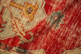 A fold reveals the distressed texture and cherry red pile of a vintage Turkish Oushak rug.