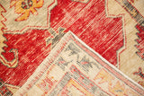 Folded corner of a vintage Oushak rug showing its hand-knotted back and distressed red pile.