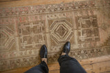 Distressed Anatolian runner featuring geometric square medallions and germinating blossom motifs.