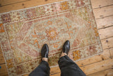 Distressed Oushak rug, showing worn pile, aubergine and green colors, and floral medallion.