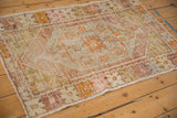 Worn pile texture and muted geometric floral motifs on a distressed vintage Oushak rug corner.
