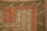 Corner of Vintage Distressed Kars rug showing heavy abrashes, finned leaf border, and pink tones.