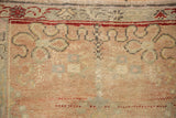 Detail of the distressed Oushak rug's low, hand-knotted pile and faded geometric floral motifs.