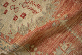 Soft, hand-knotted texture of a distressed Oushak rug, with a corner folded to show the low pile.