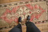 Distressed Oushak runner's stepped medallion, geometric patterns, and faded red, ivory, pale green pile.