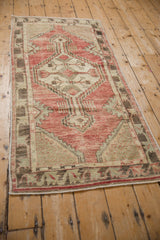 Hand knotted distressed Oushak runner with faded red, ivory, and celadon geometric medallion.