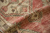 Distressed pile texture and faded cherry red geometric patterns on a vintage Oushak runner.