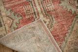 Vintage distressed Oushak runner corner showcasing faded red geometric pile and hand-knotted back.