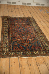 Antique Hamadan rug corner featuring ivory border with meandering boteh motifs and tattered fringe.