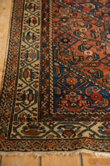 Antique Hamadan rug detail: geometric border in ivory, sapphire blue, madder red, with visible edge wear.
