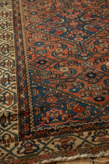 Antique Hamadan rug detail: intricate ivory geometric border and madder red Herati field.