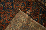 Antique Hamadan rug's hand-knotted foundation, madder red pile with Herati motif, and tattered fringe.