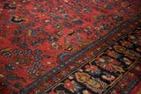 Hand-knotted Hamadan rug showing floral sprays, raspberry red field, and navy blue border.