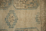 Distressed texture and abrashed ground of the Ersari carpet, with dusty teal and brown geometric guls.