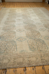 Distressed Ersari carpet with repeating geometric guls in soft teal and beige, showing worn pile.
