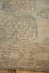 Distressed vintage Ersari carpet texture with beige and dusty teal geometric guls and border.