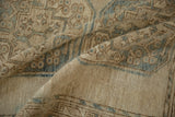 Folded vintage distressed Ersari carpet, highlighting worn beige pile and ocean green guls.