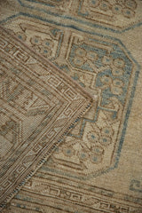 Folded vintage Ersari carpet shows hand-knotted foundation, geometric design, and distressed beige, teal pile.