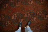 Distressed Ersari carpet close-up, showing octagonal guls, chestnut red, blush rose, and abrash.