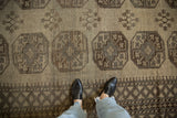 Textured beige and brown distressed Ersari rug pile, highlighting geometric guls underfoot.