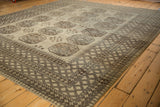 Distressed Ersari carpet corner with multiple geometric diamond borders in beige and brown.