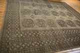 Distressed vintage Ersari rug's geometric diamond borders in beige and coffee brown hues.