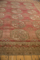 Angled view of a vintage Ersari carpet's low, distressed pile and repeating hexagonal gul pattern.