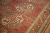 Time-softened texture of a distressed Ersari carpet with raspberry red and oxidized silver gul medallions.