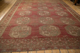 Angled perspective of a distressed Ersari carpet with geometric gul medallions and time-softened raspberry red hues.