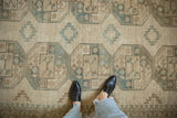 Distressed vintage Ersari carpet's ivory and dusty ocean green geometric gul medallions.