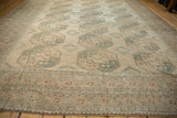 Corner detail of distressed vintage Ersari carpet, geometric border patterns in beige and dusty ocean green.