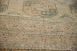 Distressed Ersari carpet's faded geometric patterns and textural wear in sand and ocean green.