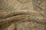 Distressed pile of an Ersari rug featuring geometric gul motifs in beige and dusty green.