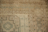 Distressed vintage Ersari carpet corner, with geometric patterns in beige, ivory, and dusty teal.