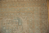 Distressed vintage Oushak rug corner, showing pale coffee brown and dusty teal geometric borders with even wear.