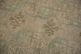 Close-up of vintage distressed Oushak rug, showing faded beige and pale teal floral-geometric patterns.
