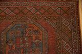 Vintage Ersari carpet corner showing diamond and vine borders, distressed pile, dusty burgundy, dark teal tones.