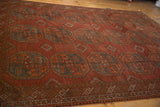 Distressed Ersari carpet detail: dusty red gul medallions, diamond guls, germinating plants, and abrashed pile.