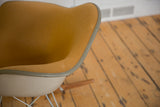 Angled view of the original Girard fabric's texture and piping on a vintage Eames rocking chair.