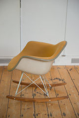 Side profile of an Eames rocker with textured mustard Girard fabric and wood base.