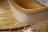 Detailed view of the vintage Eames chair's textured fiberglass shell and fabric edge.