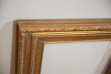 Ornate leaf carving detail on a vintage golden wood picture frame.