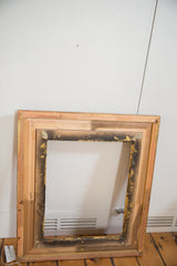 Back of vintage golden wood picture frame, showing raw wood construction and gold details.
